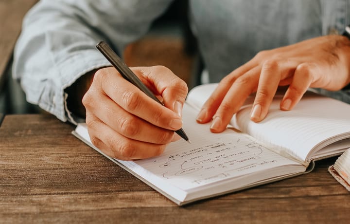 tiro de cerca de las manos de una persona escribiendo en una libreta